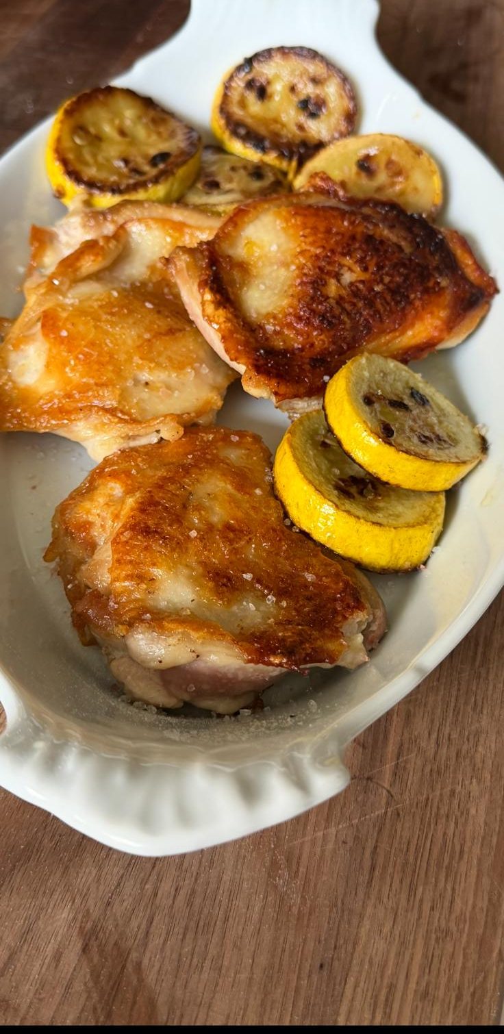 Seared chicken thighs with golden squash rounds on a plate.